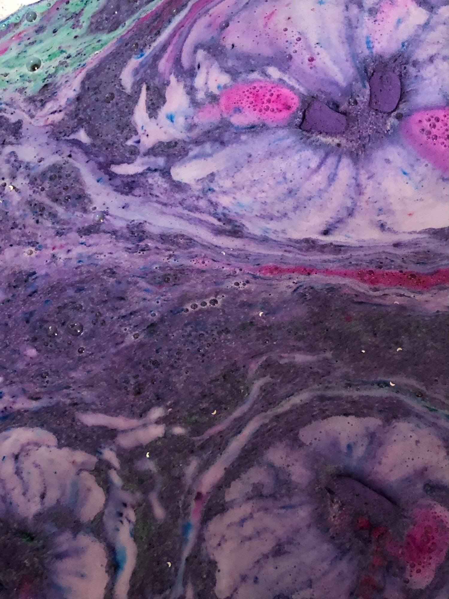 Purple and pink bath bomb foam and fizz in a tub 